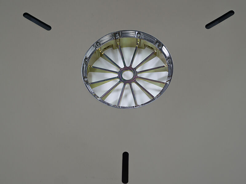 Image shows the inside of the precision reflector dish. The interior of the dish is painted a tan color. Image shows the center metallic component that has spokes. There are 3 small rectangular cutouts on the surface of the dish radiating from the center.